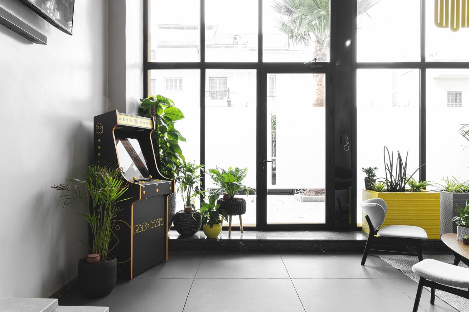 Coin détente avec machine d'arcade Pac-Man et plantes vertes chez Mow, espace coworking à Casablanca, offrant une ambiance ludique et relaxante