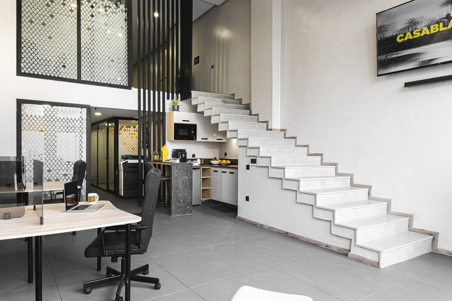 Espace de coworking moderne chez Mow, à Casablanca, avec kitchenette équipée, bureaux partagés et escalier design, créant un environnement de travail inspirant et fonctionnel.