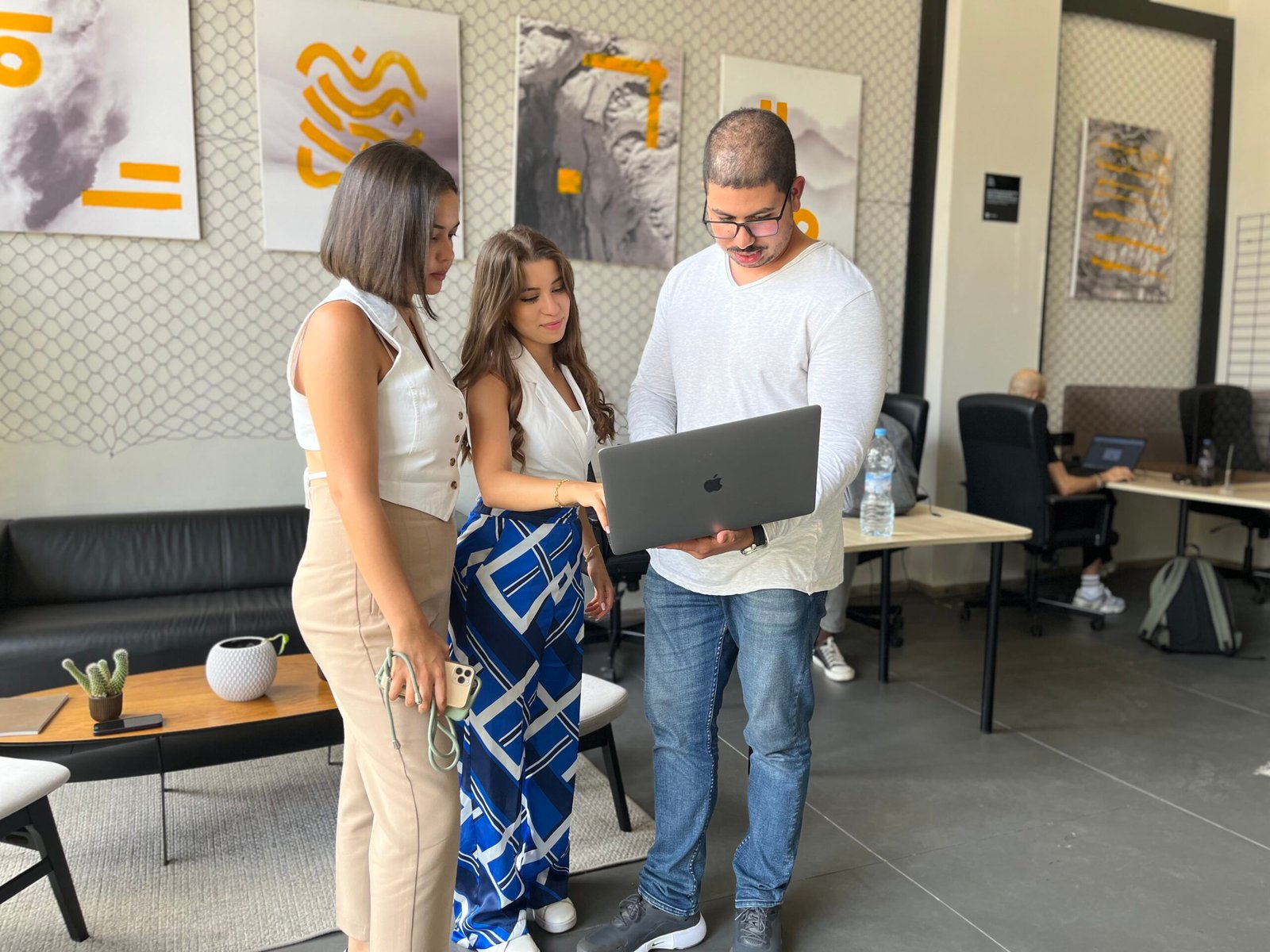 Trois professionnels de Mow travaillant ensemble sur un ordinateur portable dans un bureau moderne