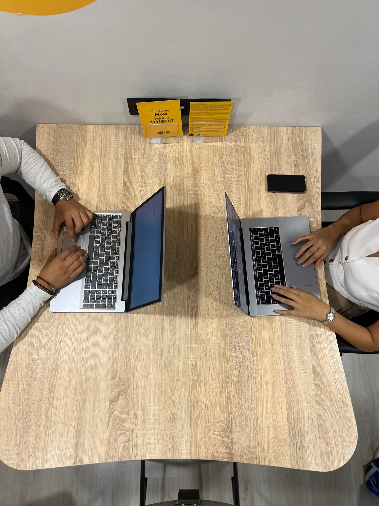 Vue de dessus de deux employés de Mow utilisant des ordinateurs portables à une table de bureau, travaillant sur des projets collaboratifs