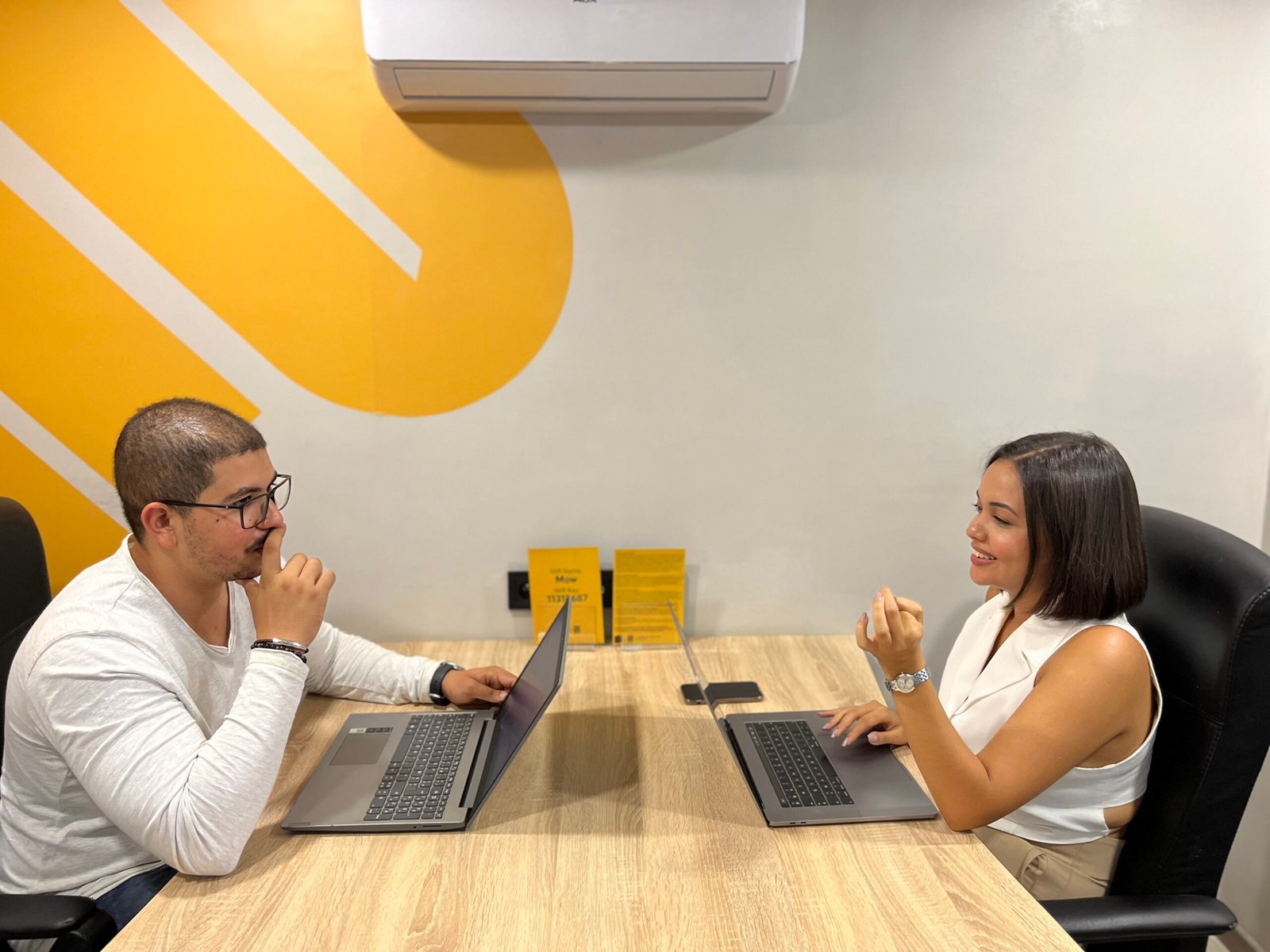 Deux professionnels échangeant des idées sur des projets avec des ordinateurs portables dans un espace de bureau éclairé chez Mow