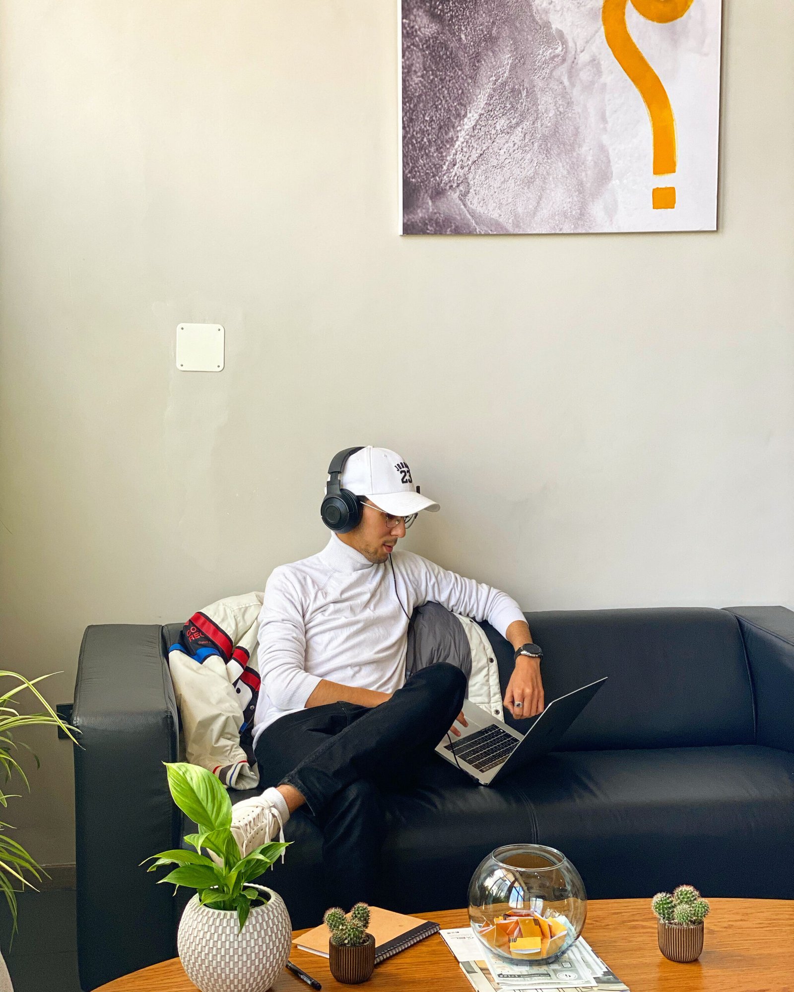 Employé de Mow travaillant sur un ordinateur portable en portant des écouteurs, confortablement installé sur un canapé dans un espace détente stylisé