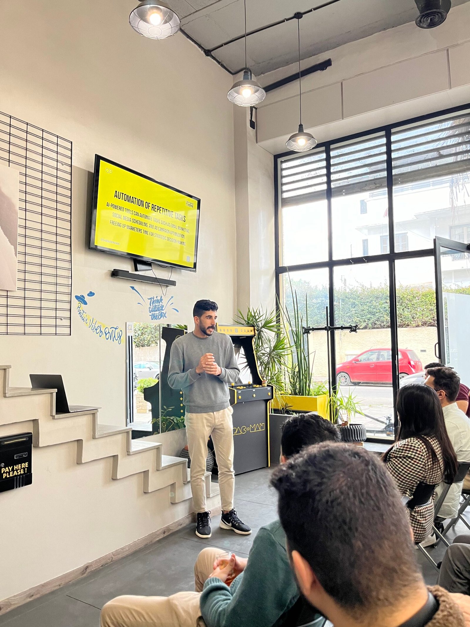 Conférencier chez Mow présentant devant un écran jaune vibrant, captivant une audience attentive dans un bureau moderne avec éclairage naturel