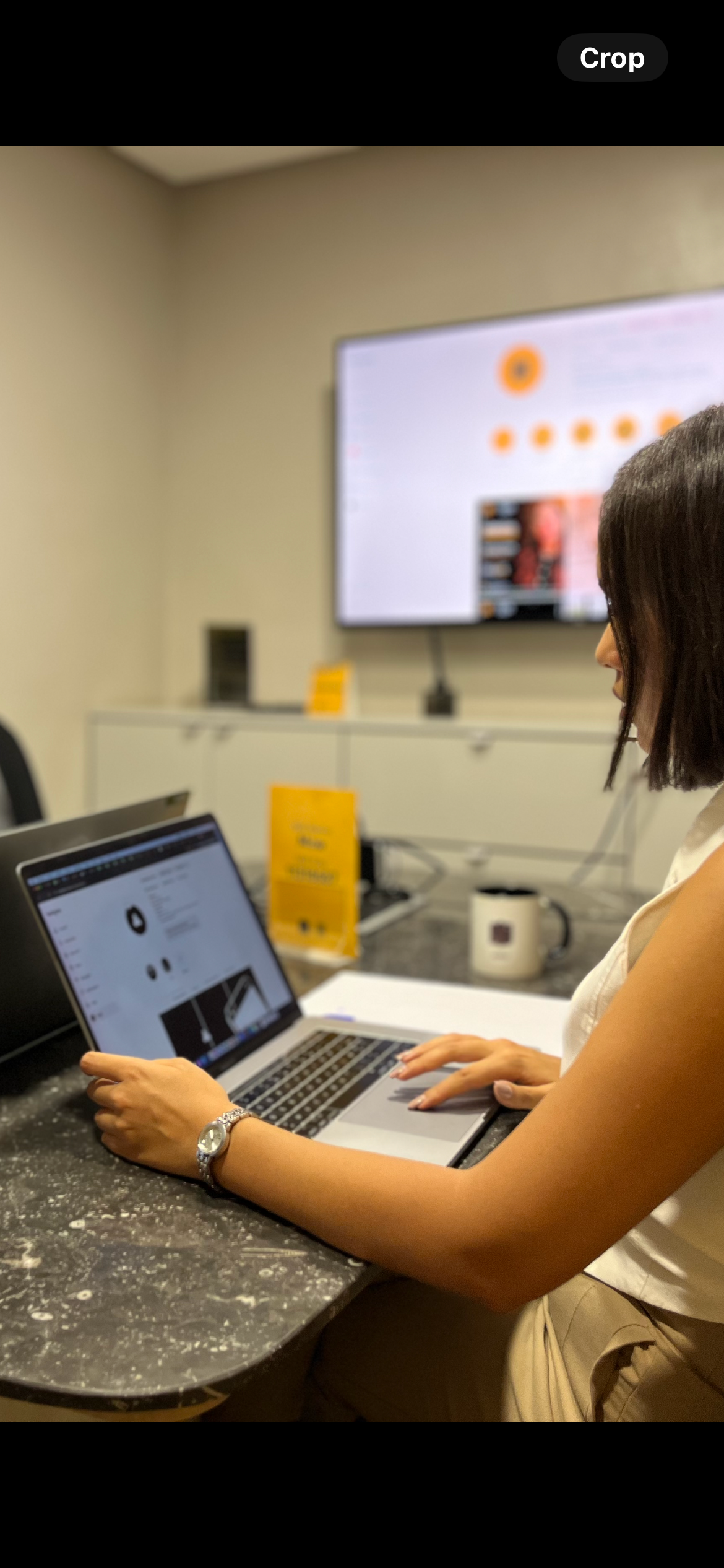 Employée de Mow travaillant sur un ordinateur portable avec un écran de gestion de projet en arrière-plan dans un bureau moderne