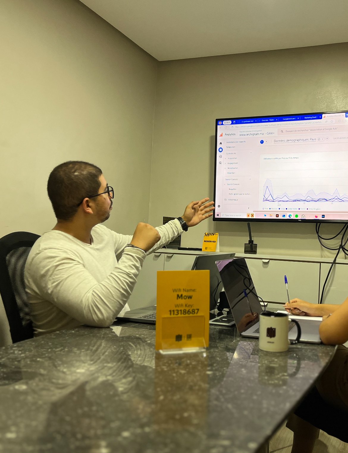 Employé de Mow présentant des métriques de performance sur un grand écran lors d'une réunion d'équipe dans un bureau