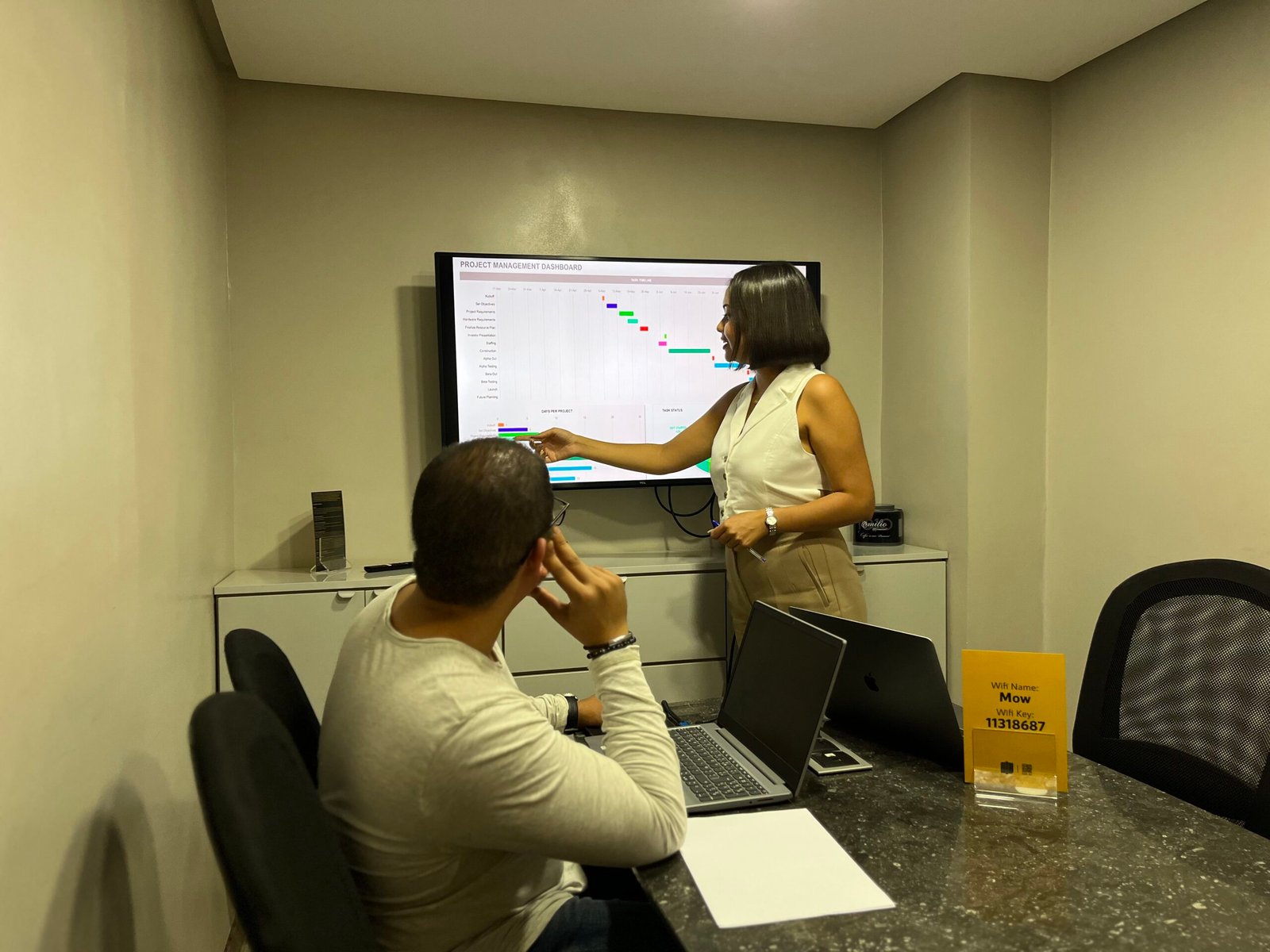 Une femme présentant des données sur un écran à un collègue masculin dans un bureau chez Mow