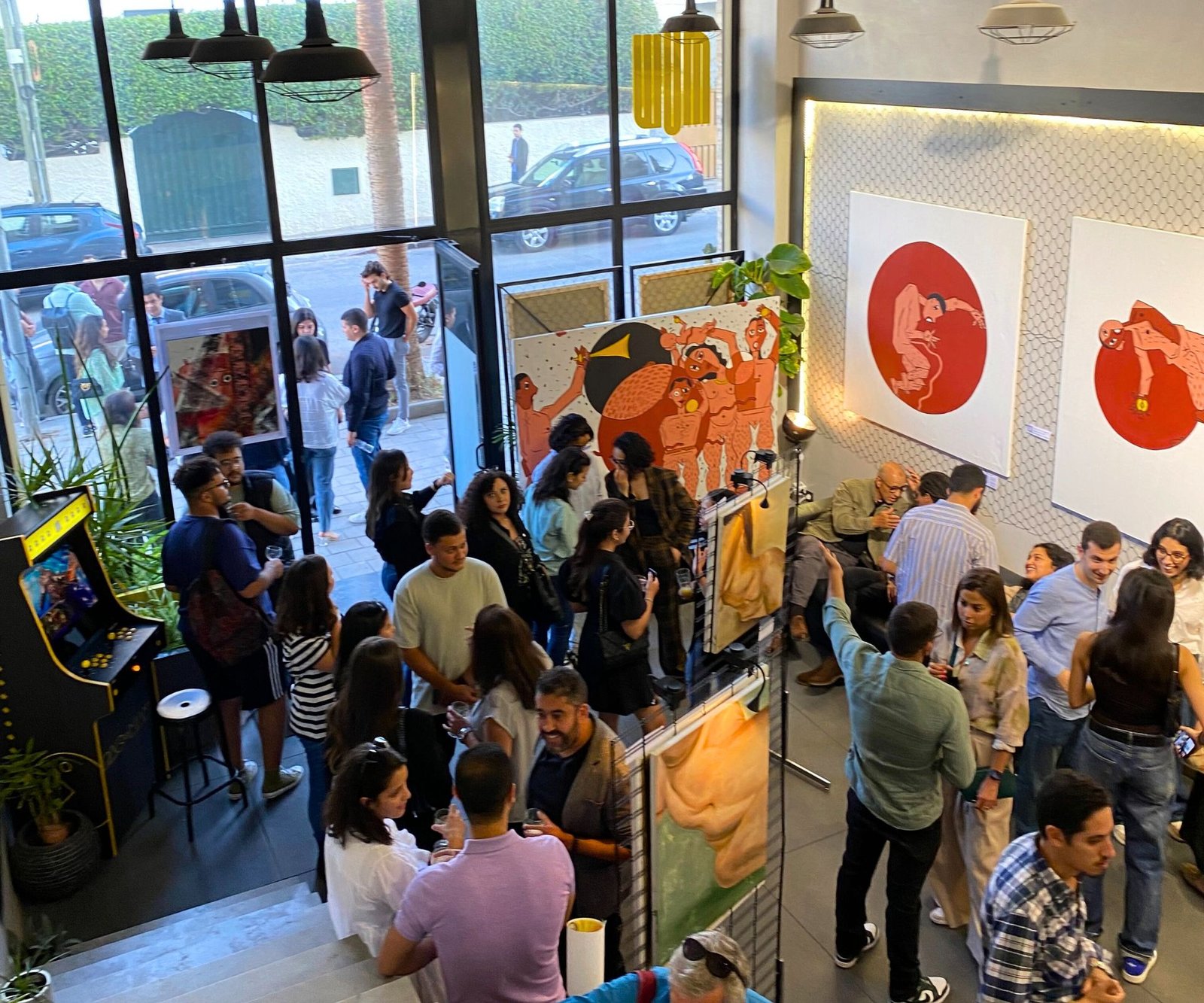 Vue d'ensemble d'une exposition artistique animée au coworking MOW à Casablanca, avec des visiteurs explorant les œuvres et discutant.