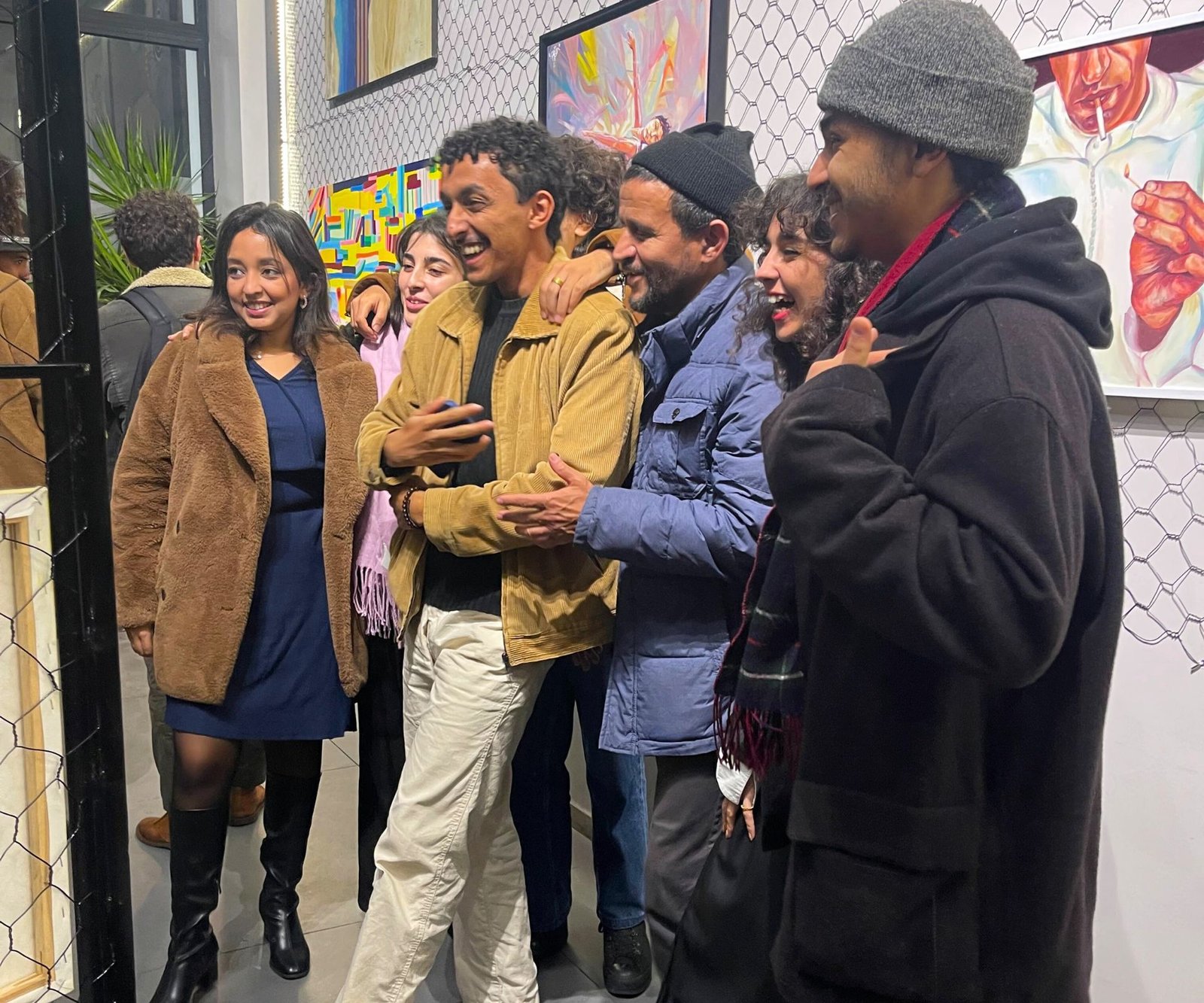 Groupe de personnes souriantes posant ensemble lors d'une exposition artistique au coworking MOW à Casablanca.